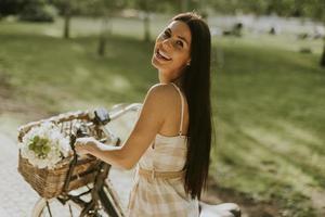 giovane donna con fiori nel cestino della bici elettrica foto