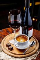 una bottiglia di vino rosso con una tazza di caffè e cioccolato