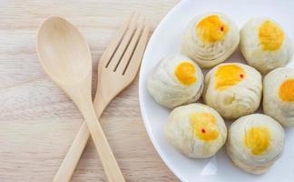 fagiolo cinese della pasticceria o mooncake con tuorlo d'uovo sul piatto e forchetta del cucchiaio di legno della tavola foto