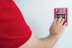 l'uomo sta raggiungendo la sua mano per spingere la stazione manuale dell'allarme antincendio foto