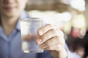 l'uomo beve acqua pura fredda fresca in vetro foto