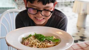 ragazzo felice mangiare spaghetti alla carbonara ricetta - la gente si diverte con il famoso concetto di cibo piatto italiano foto