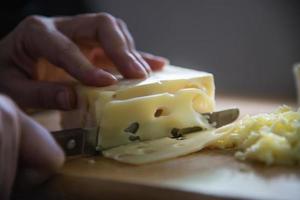 donna che prepara il formaggio per cucinare usando la grattugia in cucina - persone che producono cibo con il concetto di formaggio foto