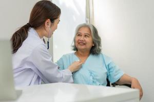 medico che esamina il cuore con uno stetoscopio e parla con una donna anziana in una clinica per il controllo annuale, il servizio sanitario di medicina e il concetto di assicurazione medica. foto