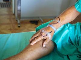 la mano del paziente anziano sta somministrando sangue durante il trattamento dell'anemia in ospedale foto