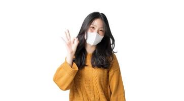 giovane donna asiatica che indossa una maschera igienica per prevenire l'infezione da virus corona inquinamento atmosferico pm2.5 isolato su sfondo bianco foto