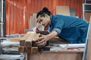 giovane falegname asiatico che lavora nel laboratorio di falegnameria di woodcraft. foto