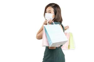 la giovane donna asiatica che tiene la borsa della spesa indossa la maschera per il viso su sfondo bianco isolato .goditi il concetto di covid-19 del negozio felice foto