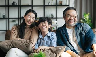 ritratto di felice famiglia asiatica che trascorre del tempo insieme sul divano in soggiorno. concetto di famiglia e casa. foto