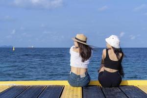 due donne amiche o coppie che si rilassano e guardano insieme le viste sulla spiaggia tropicale viaggiano per le vacanze estive. le turiste amano viaggiare nella natura esotica nel loro tempo libero. concetto di amicizia foto