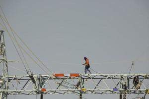 maschio che cammina sulla trave in acciaio installazione di pali elettrici di trasmissione ad alta tensione foto