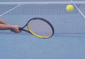 uomo che tiene la racchetta in procinto di colpire una palla nel campo da tennis foto