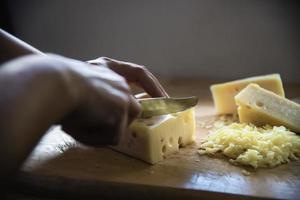 donna che prepara il formaggio per cucinare usando la grattugia in cucina - persone che producono cibo con il concetto di formaggio foto