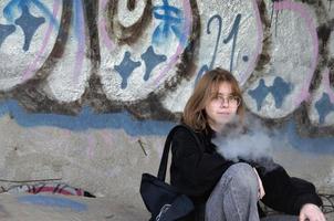 st. pietroburgo, russia, 06.01.2022. un'adolescente siede in un edificio abbandonato dipinto con graffiti e fuma foto