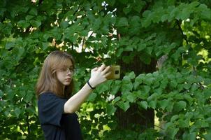 una ragazza si fotografa con il telefono vicino agli alberi foto