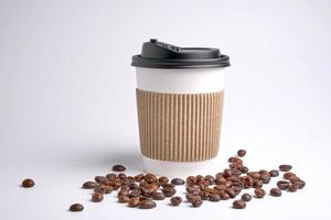 tazza di caffè di carta su fondo bianco. Il primo piano è chicchi di caffè. foto