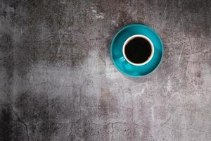 caffè nero in una tazza di ceramica blu sul vecchio pavimento di cemento grigio foto