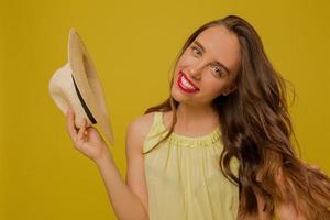 felice amabile ragazza alla moda con ondulati capelli castano chiaro con labbra rosa che indossano una camicia gialla in posa su sfondo giallo foto