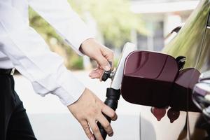 l'uomo sta mettendo ngv, veicolo a gas naturale, erogatore di testa in un'auto presso la stazione di servizio in Thailandia foto