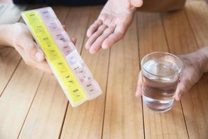 il medico assiste il paziente a mangiare correttamente la compressa di medicina nel portapillole - concetto medico delle persone foto