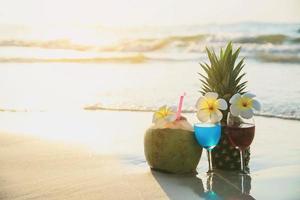 bicchieri da cocktail con cocco e ananas sulla spiaggia di sabbia pulita - frutta e bevande sul concetto di backgroudn della spiaggia del mare foto