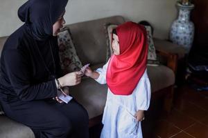 tradizione del popolo indonesiano durante la celebrazione di eid mubarak della distribuzione di denaro o chiamata thr. la donna musulmana asiatica dà soldi a un ragazzo carino di famiglia durante idul fitri. foto