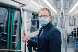 l'inquadratura del giovane indossa occhiali e maschera protettiva per prevenire la diffusione della malattia di coronavirus o dell'epidemia di influenza nei trasporti pubblici, posa su una carrozza della metropolitana vuota. soluzione di salute pubblica foto