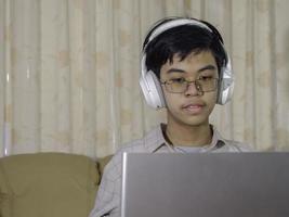 preteen scolaro che indossa le cuffie per imparare online guardando la lezione di classe guardando il computer portatile per studiare. l'apprendimento a distanza e l'istruzione restano a casa. foto