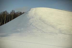 montagna di neve. pendio nevoso. giorno d'inverno. il sole splende sulla collina. oggetto naturale nel parco. foto