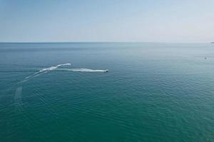 riprese ad alto angolo e vista aerea dell'oceano con barche ad alta velocità, le persone si divertono e si godono il clima più caldo a Bournemouth Beach, di fronte al mare dell'Inghilterra, Regno Unito. foto