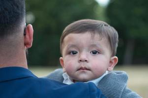 il padre pakistano asiatico tiene in braccio il suo bambino di 11 mesi nel parco locale foto