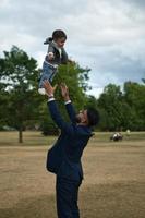 il padre pakistano asiatico tiene in braccio il suo bambino di 11 mesi nel parco locale foto