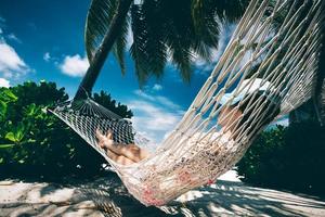 donna che si rilassa all'ombra delle palme su un'amaca. foto