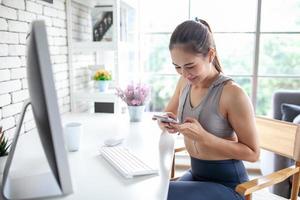 giovane donna asiatica che utilizza un computer portatile controllando l'applicazione dei social media sul sito Web online a casa, rilassati e divertiti a comunicare e discutere in soggiorno. foto