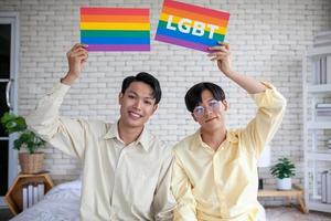 coppia gay asiatica che tiene il segno arcobaleno lgbt a casa, concetto lgbtq. foto