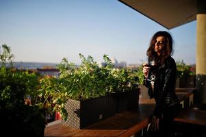 giovane donna riccia godendo il suo vino in un bar. foto