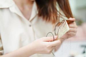 la donna asiatica ha problemi con la caduta dei capelli lunghi attaccata alla spazzola del pettine. foto