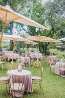 composizione floreale per il matrimonio estivo, fatta di rose e rami verdi su un tavolo da pranzo nel ristorante. , bicchieri e piatti nel ristorante all'aperto in una giornata ventosa con effetto grana della pellicola foto