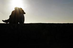 sagoma di giovane coppia seduta su un muro foto