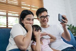 famiglia asiatica che si fa un selfie, sorride al telefono a casa. foto