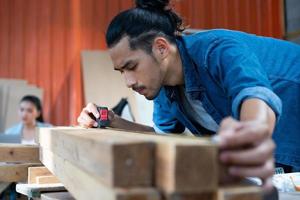 giovane falegname asiatico che lavora nel laboratorio di falegnameria di woodcraft. foto