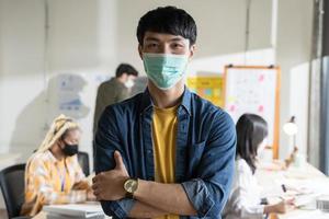 giovane asiatico con maschera facciale per protezione e prevenzione covid-19 ritratto in ufficio. al lavoro dopo il lockdown foto