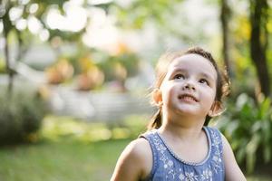 ritratto bambina nel parco naturale. bambini carini che guardano in alto foto