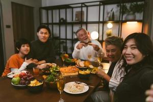 famiglia asiatica che si fa selfie prima di cena al tavolo da pranzo a casa foto