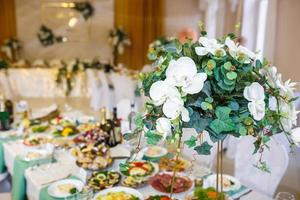 bellissimi fiori su un'elegante tavola da pranzo nel giorno del matrimonio. decorazioni servite sulla tavola festiva su sfondo sfocato foto