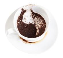 tazza bianca con sedimenti di caffè sul piattino foto