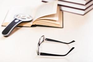 occhiali da vista e lente d'ingrandimento vicino a una pila di libri foto