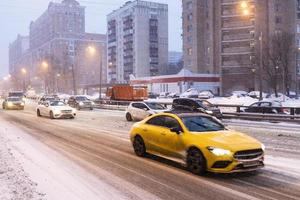 le auto guidano su una strada scivolosa nel crepuscolo invernale rosa foto