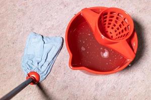 mop pulizia pavimenti in linoleum vicino al secchio rosso foto