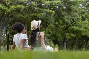 la diversità della coppia lesbica lgbtq è rilassata insieme sul prato nel parco pubblico durante la stagione estiva per godersi il concetto di tempo libero foto